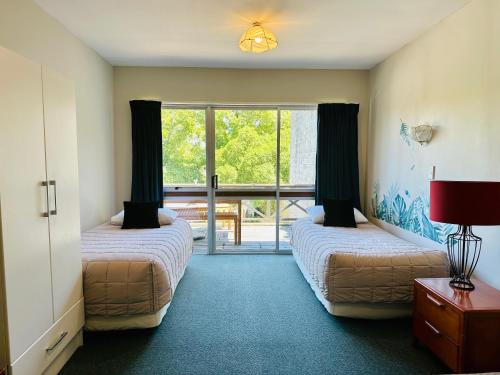 a room with two beds and a door to a patio at A1 Kaikoura Motel & Holiday Park in Kaikoura