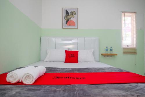 a bedroom with a red pillow and towels on a bed at RedDoorz near Tugu Kartasura in Sukoharjo