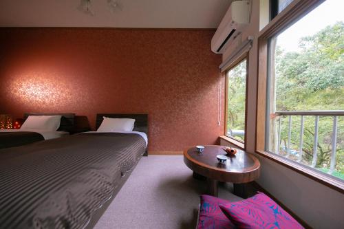 a bedroom with two beds and a table and a window at Nagahigawa in Miyazaki