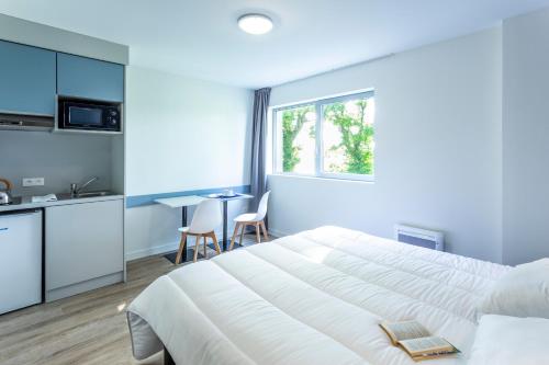 Vern-sur-SeicheにあるAtao Residence- Rennes Sudのベッドルーム(大きな白いベッド1台、テーブル付)