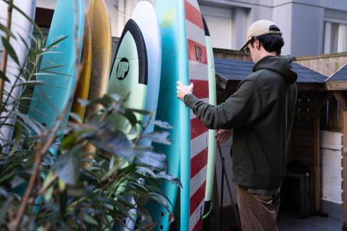 a man is standing next to three surfboards at Koba Hostel in Donostia-San Sebastián