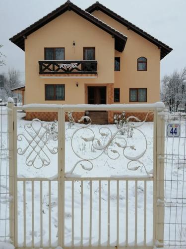 um portão em frente a uma casa coberta de neve em Pensiunea Aryana em Crasna din Deal