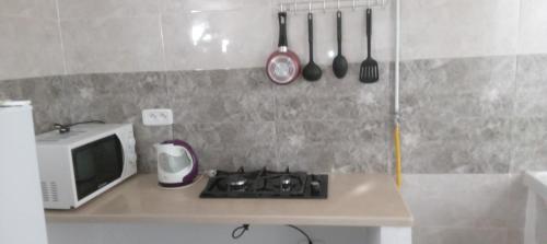 a kitchen with a stove and a microwave on a counter at Studio, Cité la GAZELLE ,pas Jafar, quartier calme 10 min de l'aéroport près du Technopark in Jafar