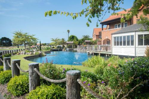 un étang dans un jardin avec une clôture dans l'établissement Compass Cottage - Monaco Resort, à Nelson