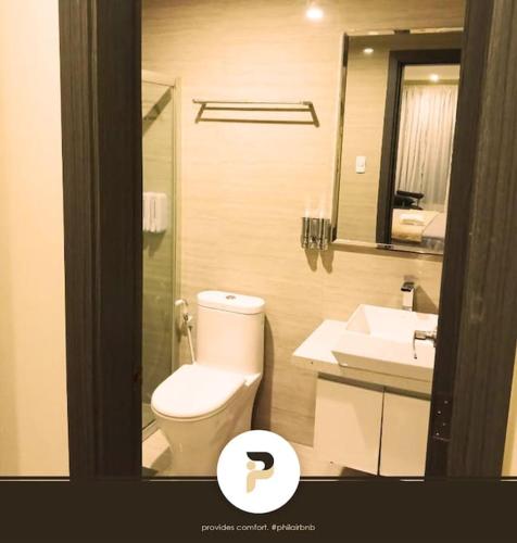 a bathroom with a toilet and a sink and a mirror at SPACIOUS 1BR NEAR SOLAIRE & SM MOA in Manila