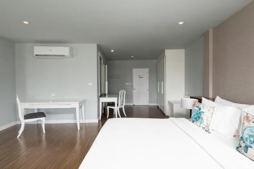 a bedroom with a white bed and a desk at Arinara Beach Resort Phuket - SHA Extra Plus in Bang Tao Beach