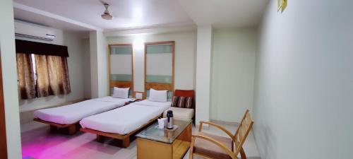 two beds in a room with a table and chairs at Hotel Easy Retreat in Vapi