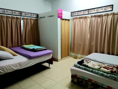 キャメロンハイランドにあるSakura Guest Houseのカーテン付きの部屋にベッド2台が備わる部屋