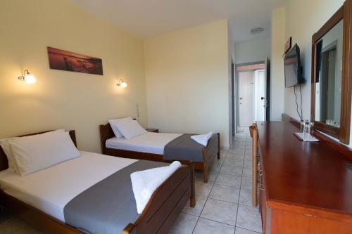 una camera d'albergo con due letti e una televisione di Iraklis Hotel a Mitikas