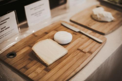 a wooden cutting board with cheese and a knife at Agriturismo Tenuta La Romana in Nizza Monferrato