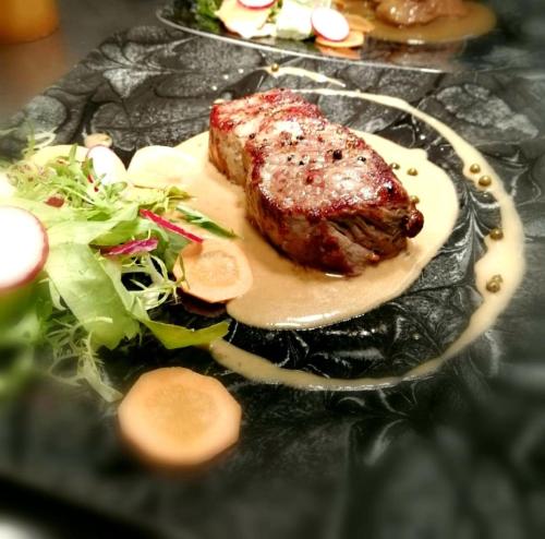 a plate of food with a piece of meat and a salad at Hotel Südlohner Hof - Ristorante Da Fabio in Südlohn