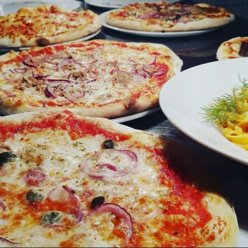 a group of pizzas sitting on plates on a table at Hotel Südlohner Hof - Ristorante Da Fabio in Südlohn