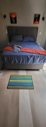 ein Schlafzimmer mit einem Bett mit einem bunten Teppich auf dem Boden in der Unterkunft New apollo lodge in Roodepoort