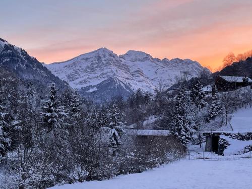 eine schneebedeckte Bergkette mit Sonnenuntergang im Hintergrund in der Unterkunft Mountain River Appart in Val dʼIlliez