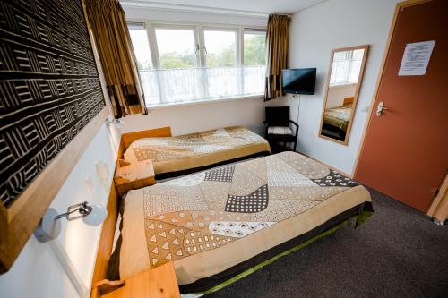 um quarto de hotel com duas camas e uma janela em Pension Westerburen em Schiermonnikoog