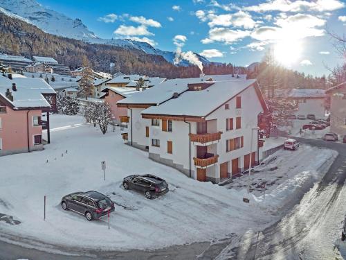 two cars parked in a snow covered town with buildings at Rosatsch 13 in Surlej