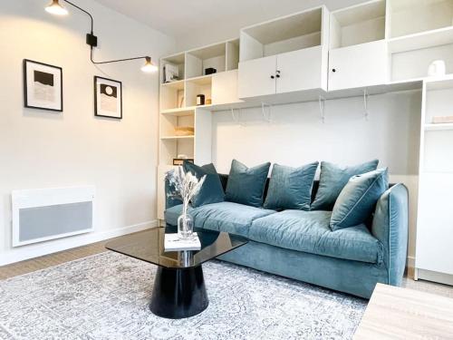 ein Wohnzimmer mit einem blauen Sofa und einem Tisch in der Unterkunft Appartement calme centre ville rénovation récente in Le Touquet-Paris-Plage