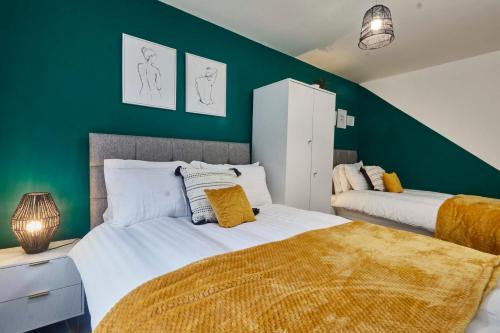 a bedroom with two beds and a green wall at Homebird Property - Salisbury House in Leeds