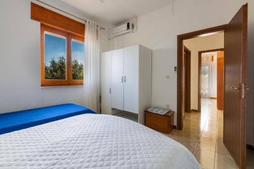 a bedroom with a white bed and a window at Villa Santina by BarbarHouse in Torre Colimena