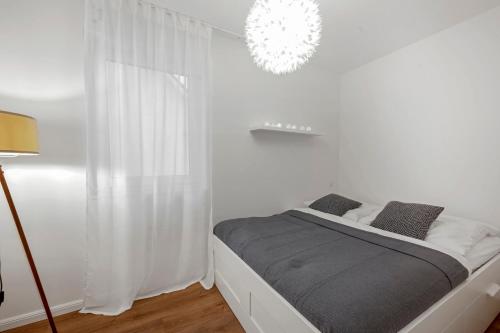 ein weißes Schlafzimmer mit einem Bett und einem Kronleuchter in der Unterkunft Nadorst Residenz in Oldenburg