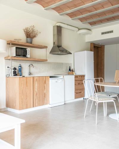 a kitchen with white appliances and a table and chairs at Can Alemany in Santa Margarida de Montbui