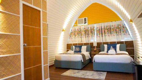 twee bedden in een kamer met een boog bij UNWND BOUTIQUE HOTEL CALATAGAN in Batangas City