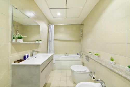 a bathroom with a toilet and a sink and a tub at Maison Privee - High-Floor Trendy Apt with Marina, Palm & Ocean Vws in Dubai