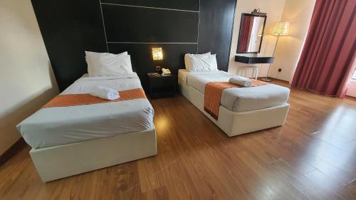 a hotel room with two beds and a chair at The Jerai Hotel Sungai Petani in Sungai Petani