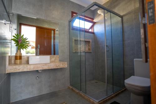 uma casa de banho com uma cabina de duche em vidro e um WC. em PARAÍSO DO DENDÊ - FLATS em Barra Grande