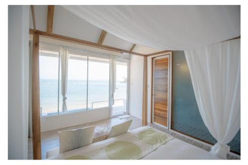 a bedroom with a large window with a view of the ocean at Seashell Village Resort in Chao Lao Beach