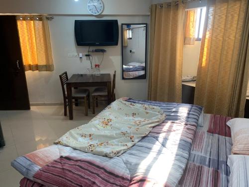a bedroom with a bed and a table and a tv at Kamil’s Studio Apartment in Lucknow