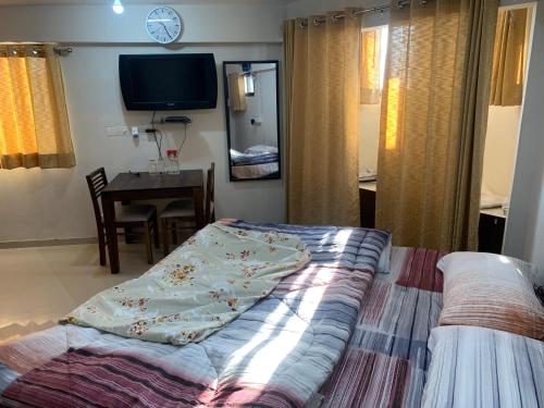 a bedroom with a bed and a tv and a table at Kamil’s Studio Apartment in Lucknow