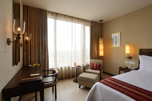 a hotel room with a bed and a chair and a window at Marasa Sarovar Premiere in Tirupati