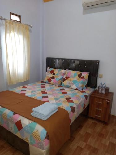 un letto con un piumone colorato in una camera da letto di Juda Homestay a Banyuwangi
