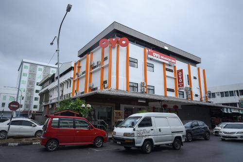 a building with cars parked in a parking lot at Super OYO 976 Dragon Inn in Miri