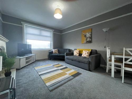 a living room with a couch and a television at Raploch House in Larkhall