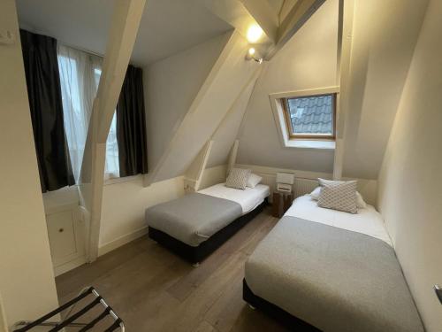 two beds in a small room with two windows at Residences Museum District in Amsterdam