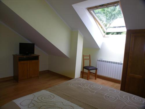 a bedroom with a bed and a tv and a window at Apartamentos Puente La Molina in Carreña de Cabrales 