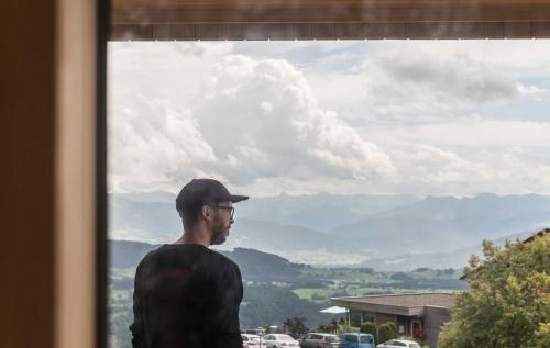 a man standing in front of a window with a view at Apartments Pôldi in Sulzberg