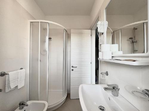 a white bathroom with a shower and a sink at Hotel Old River in Lignano Sabbiadoro