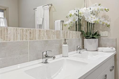 uma casa de banho com um lavatório branco e um espelho. em The Guesthouse Maleny em Maleny