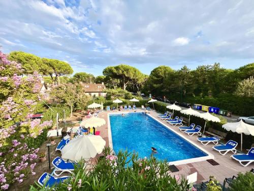 an outdoor swimming pool with umbrellas and chairs and people at Hotel Old River in Lignano Sabbiadoro