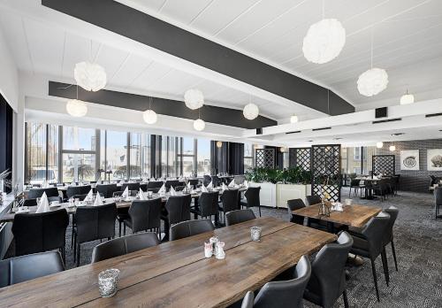 een restaurant met houten tafels, stoelen en ramen bij Østergaards Hotel in Herning