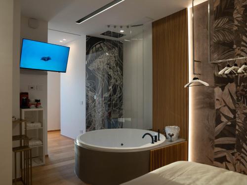a bathroom with a tub and a tv on the wall at B&B Suite Carafa 61 in Ruvo di Puglia
