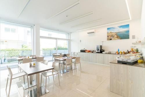 uma cozinha com mesas e cadeiras num quarto em Residenza Turistica Alberghiera Blue Marine em Bibione