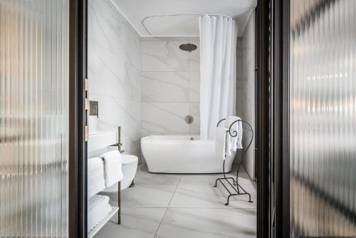 a white bathroom with a tub and a sink at Zamarin Hotel & Spa in Zikhron Ya‘aqov