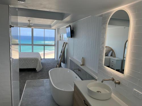 La salle de bains est pourvue d'une baignoire, d'un lavabo et d'un miroir. dans l'établissement Endless Summer in Cooly Level 18, à Gold Coast