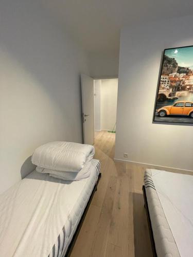 a bedroom with two beds and a painting on the wall at Maison les Bruyères in Blankenberge