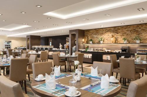 Howard Johnson Dammam Hotel في الدمام: مطعم بطاولات وكراسي وبار