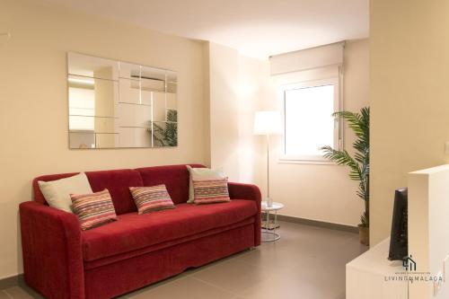 a red couch in a living room with a mirror at Living4Malaga Centro Histórico y Playa in Málaga